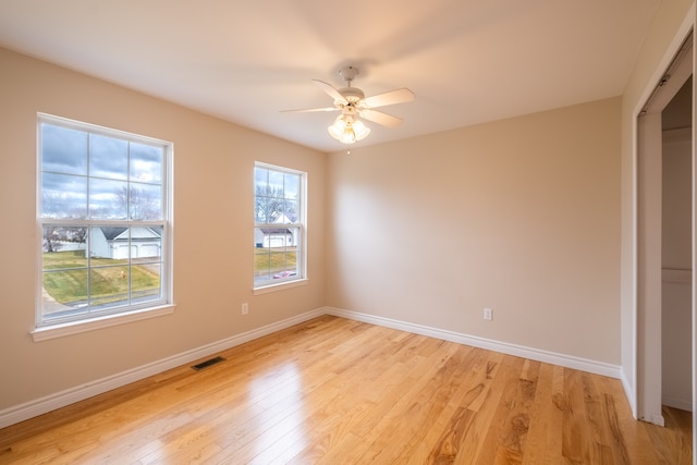 unfurnished room featuring baseboards, visible vents, and light wood-style floors