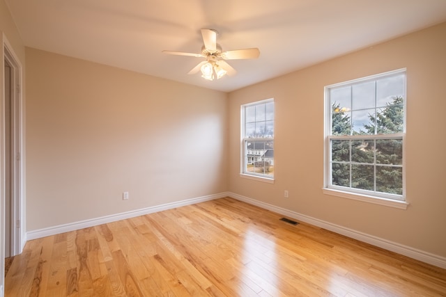 empty room featuring light wood-type flooring, visible vents, and baseboards