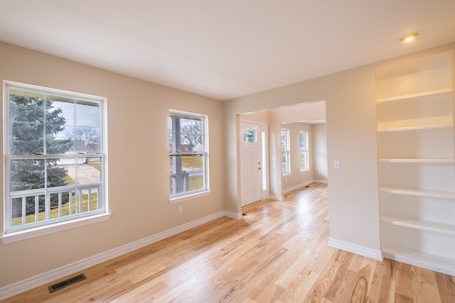 foyer entrance with visible vents, light wood-style flooring, and baseboards