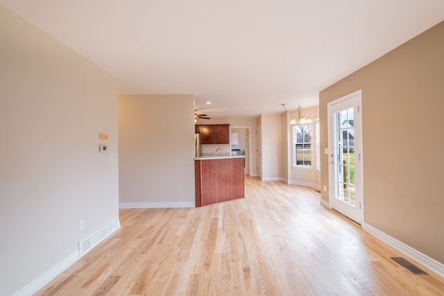 unfurnished living room with light wood-style floors, baseboards, visible vents, and a sink