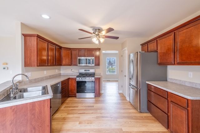 kitchen featuring stainless steel appliances, a sink, light countertops, and light wood-style floors