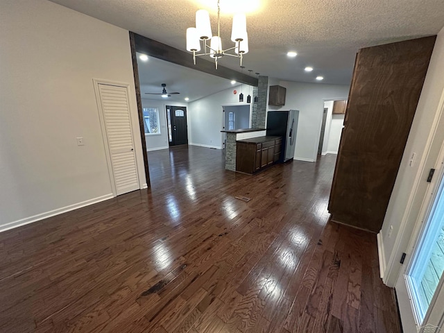 kitchen featuring a textured ceiling, open floor plan, vaulted ceiling, freestanding refrigerator, and dark wood-style floors