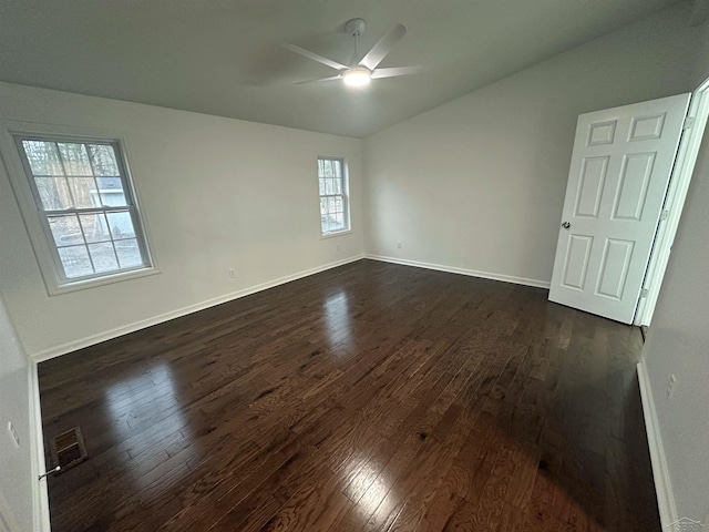 interior space with lofted ceiling, ceiling fan, dark wood-type flooring, visible vents, and baseboards