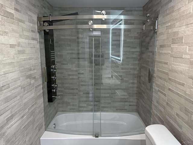 full bathroom featuring toilet and bath / shower combo with glass door