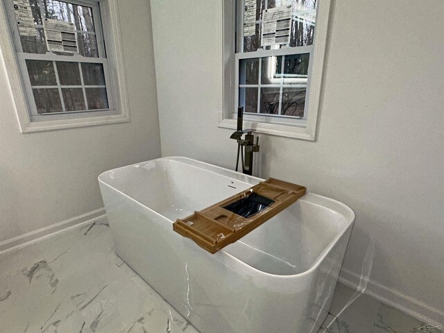 details featuring a freestanding tub and baseboards