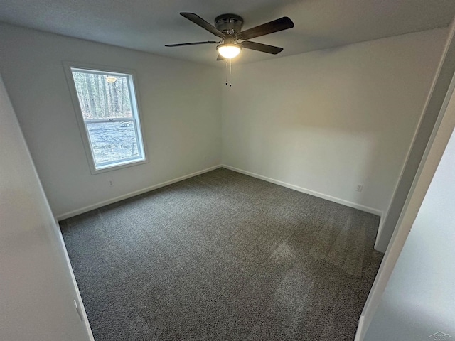 spare room with a ceiling fan, dark carpet, and baseboards