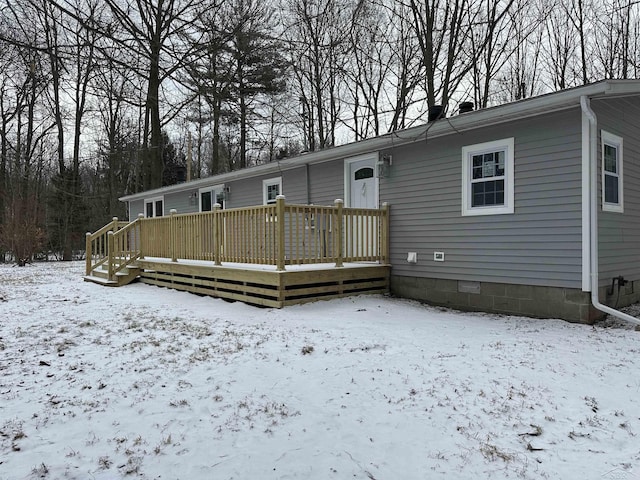 snow covered back of property featuring a wooden deck