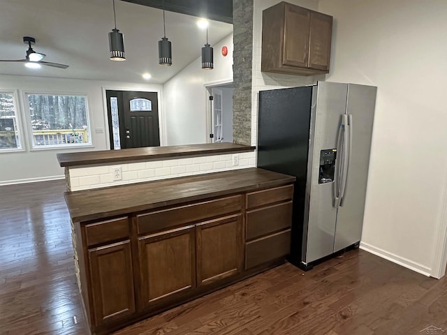 kitchen with lofted ceiling, a peninsula, dark wood-type flooring, wooden counters, and stainless steel fridge