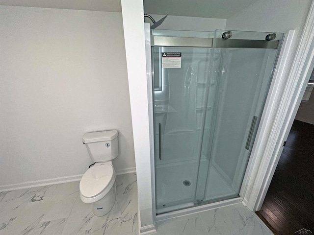 bathroom featuring toilet, marble finish floor, a shower stall, and baseboards