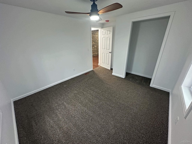 unfurnished bedroom with baseboards, dark carpet, and ceiling fan