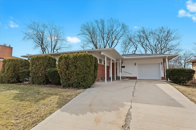 view of front facade with a front yard, a garage, brick siding, and driveway