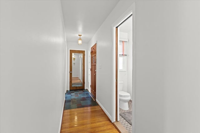 hall with light wood-type flooring and baseboards