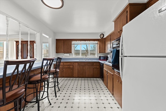 kitchen featuring light floors, black appliances, light countertops, and a sink