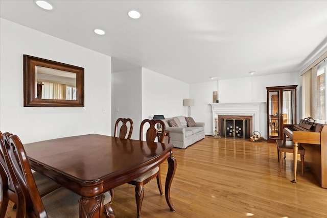 dining space with recessed lighting, light wood-type flooring, and a fireplace with raised hearth