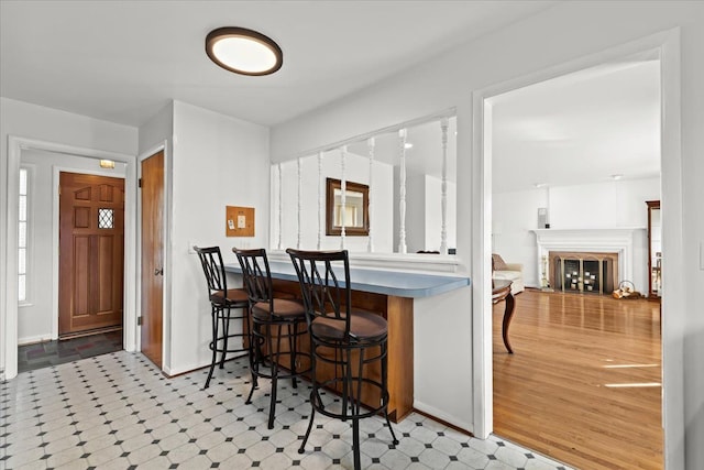 kitchen featuring tile patterned floors, a fireplace, a kitchen bar, and baseboards