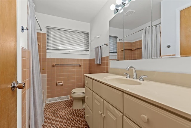 bathroom with visible vents, toilet, tile walls, and vanity