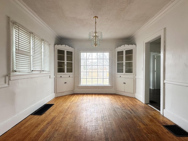 unfurnished dining area featuring a chandelier, hardwood / wood-style floors, and visible vents