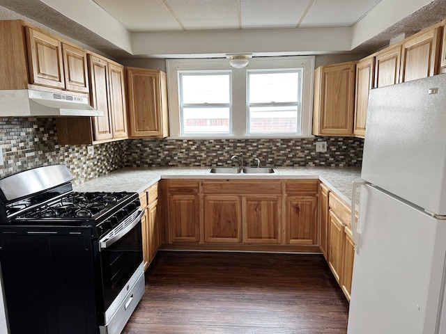 kitchen with freestanding refrigerator, stainless steel gas range, light countertops, under cabinet range hood, and a sink