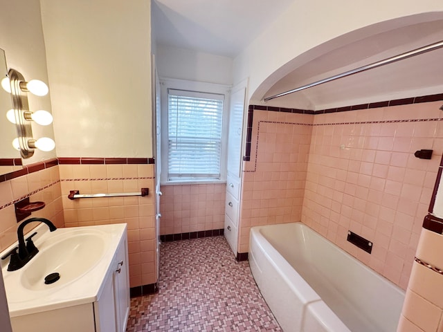 full bath with shower / bathtub combination, a wainscoted wall, vanity, and tile walls