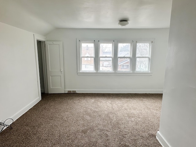 empty room with lofted ceiling, carpet floors, visible vents, and baseboards