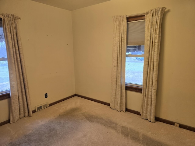 empty room with carpet, visible vents, and baseboards