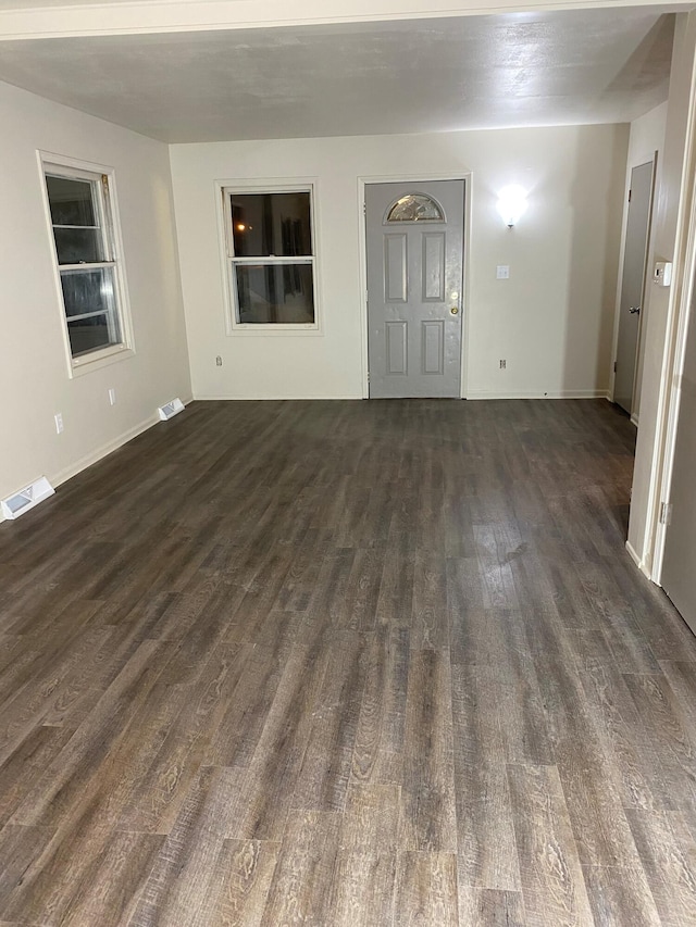 empty room with dark wood-style flooring and visible vents