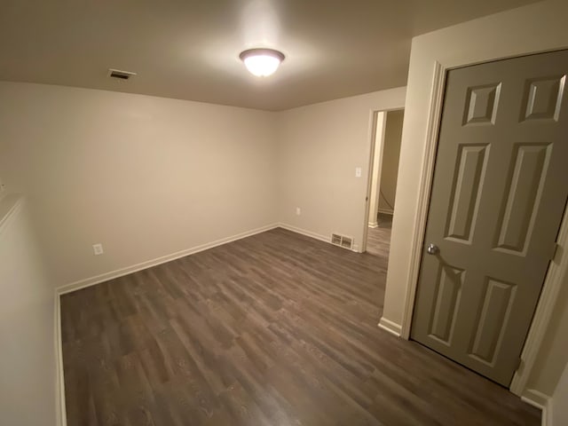 unfurnished room with visible vents, dark wood finished floors, and baseboards