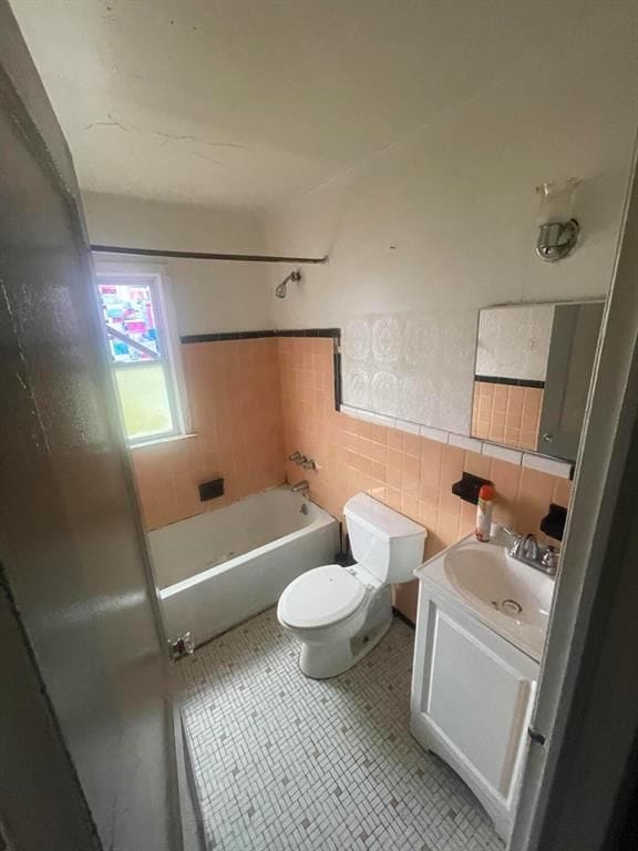 full bath featuring bathing tub / shower combination, toilet, tile patterned flooring, vanity, and tile walls