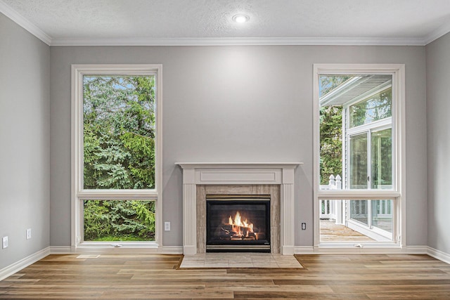 unfurnished living room with a textured ceiling, a fireplace, wood finished floors, and baseboards