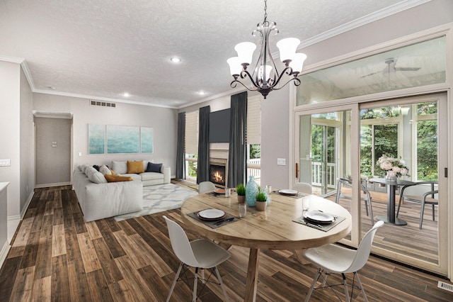 dining space featuring a textured ceiling, a fireplace, visible vents, ornamental molding, and dark wood-style floors