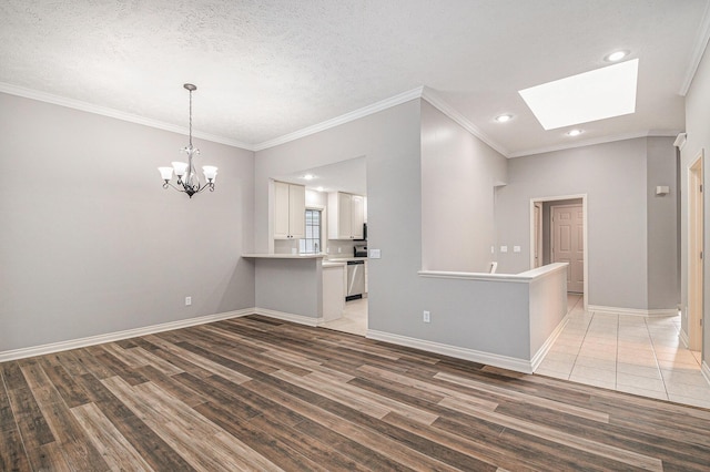 unfurnished room featuring a notable chandelier, a skylight, light wood-style flooring, and baseboards