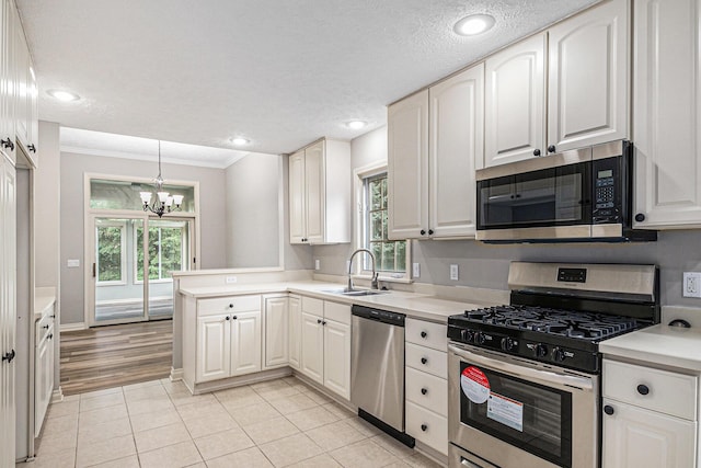 kitchen with a peninsula, a healthy amount of sunlight, stainless steel appliances, and a sink