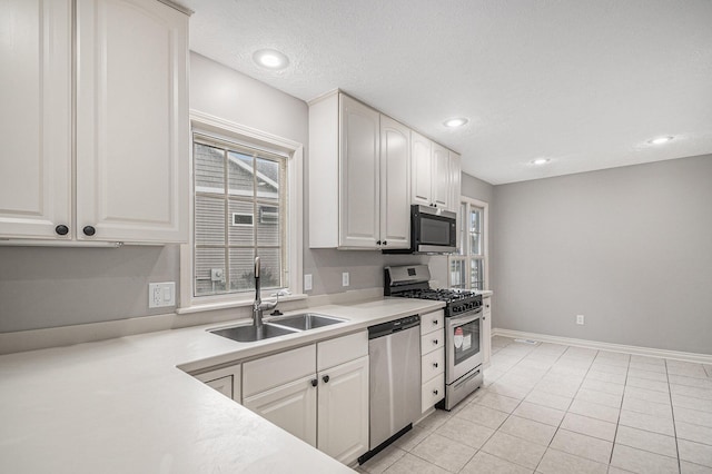 kitchen with light tile patterned floors, appliances with stainless steel finishes, light countertops, white cabinetry, and a sink