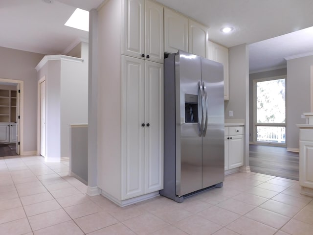 kitchen with light tile patterned floors, ornamental molding, baseboards, and stainless steel fridge with ice dispenser