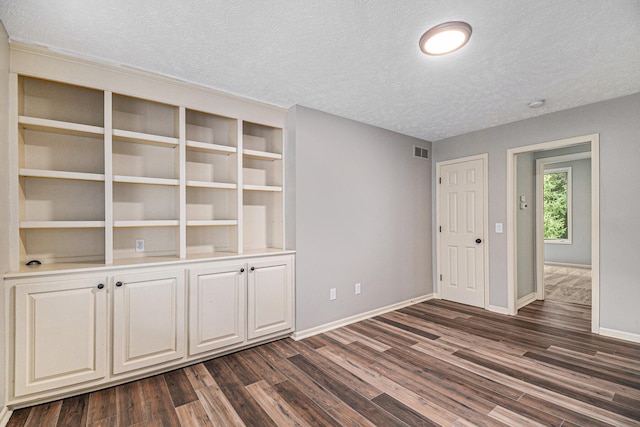 spare room with visible vents, baseboards, dark wood finished floors, and a textured ceiling