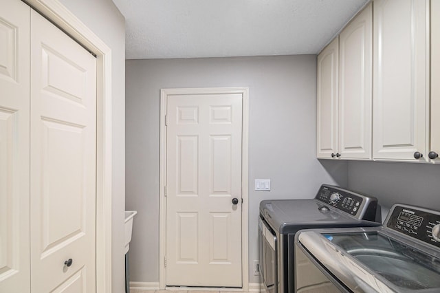 washroom featuring cabinet space, washer and clothes dryer, baseboards, and a textured ceiling