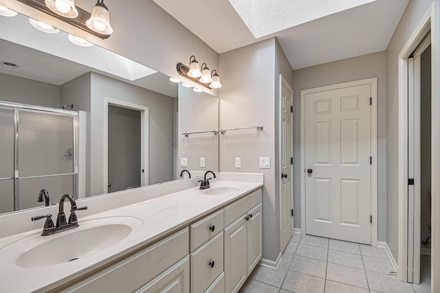 full bath featuring double vanity, a stall shower, tile patterned flooring, and a sink