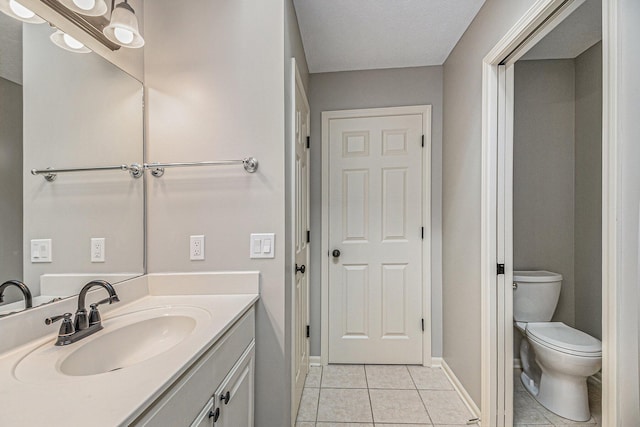 bathroom featuring vanity, tile patterned flooring, toilet, and baseboards