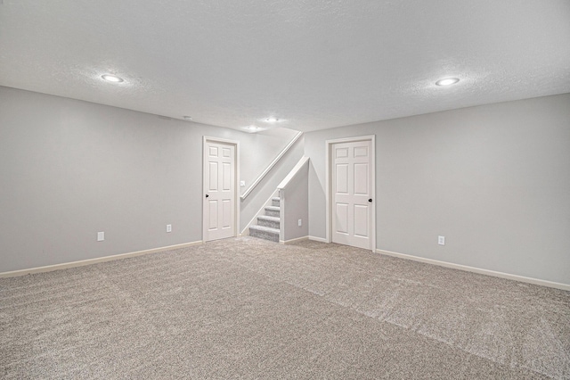 finished below grade area featuring carpet, recessed lighting, a textured ceiling, baseboards, and stairs