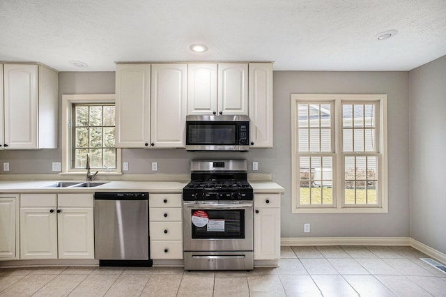 kitchen featuring stainless steel appliances, a healthy amount of sunlight, a sink, and baseboards