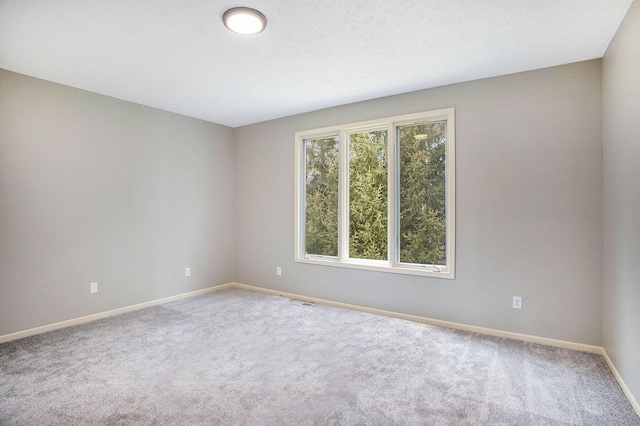 unfurnished room with carpet floors, visible vents, and baseboards