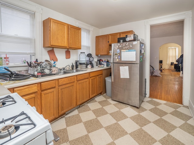 1020 S Park St, Kalamazoo, MI 49001 - kitchen featuring arched walkways, freestanding refrigerator, white gas stove, light floors, and a sink