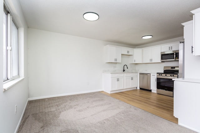 kitchen featuring baseboards, stainless steel appliances, light countertops, and white cabinets