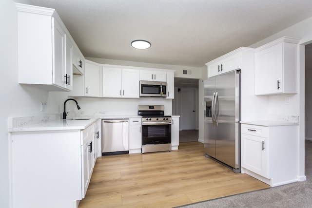 kitchen featuring appliances with stainless steel finishes, white cabinets, visible vents, and a sink