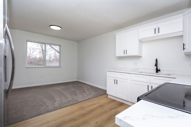 kitchen featuring black / electric stove, a sink, white cabinetry, fridge with ice dispenser, and light wood finished floors