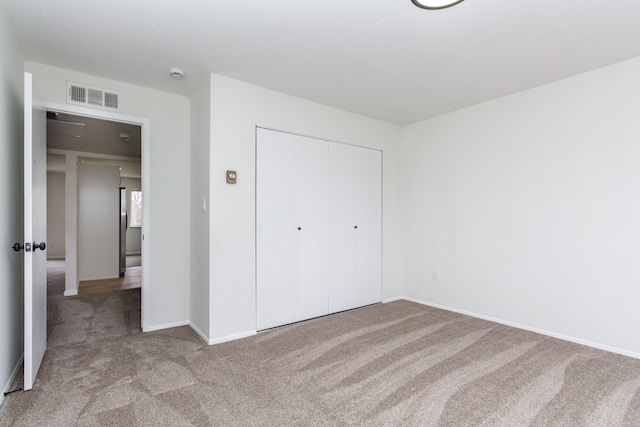 unfurnished bedroom with carpet, a closet, visible vents, and baseboards