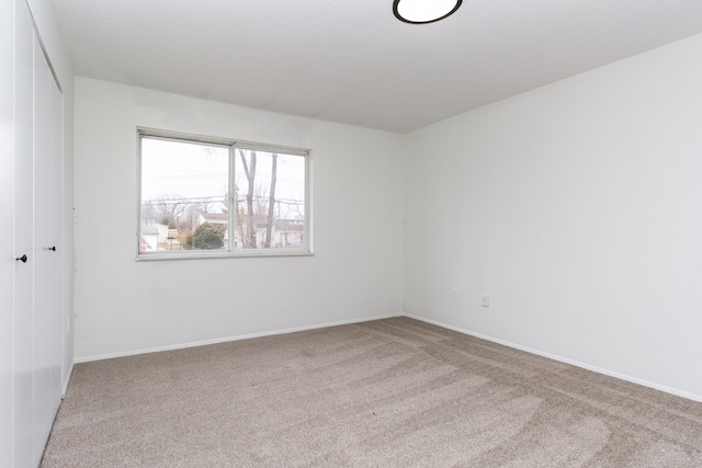 spare room featuring carpet and baseboards