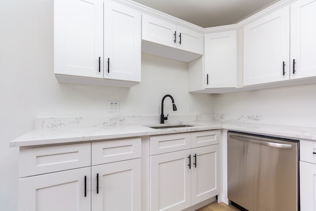 kitchen featuring light stone counters, white cabinetry, dishwasher, and a sink