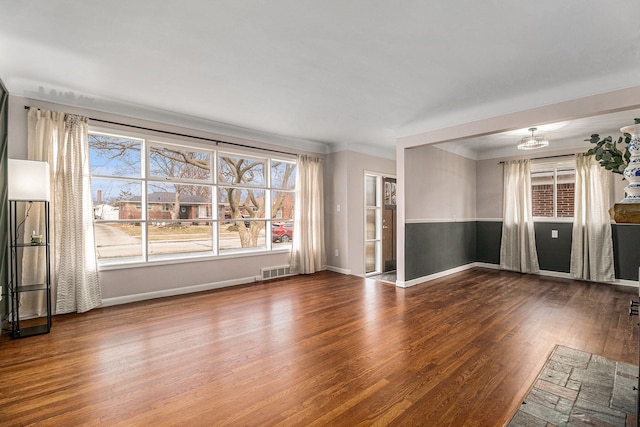 unfurnished living room with visible vents, baseboards, and wood finished floors