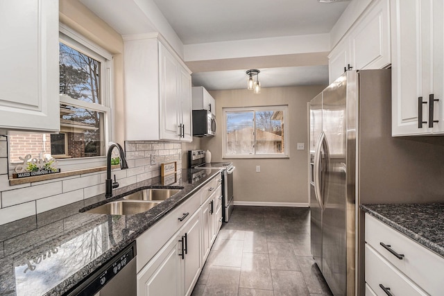 kitchen featuring stainless steel appliances, white cabinetry, a sink, and backsplash